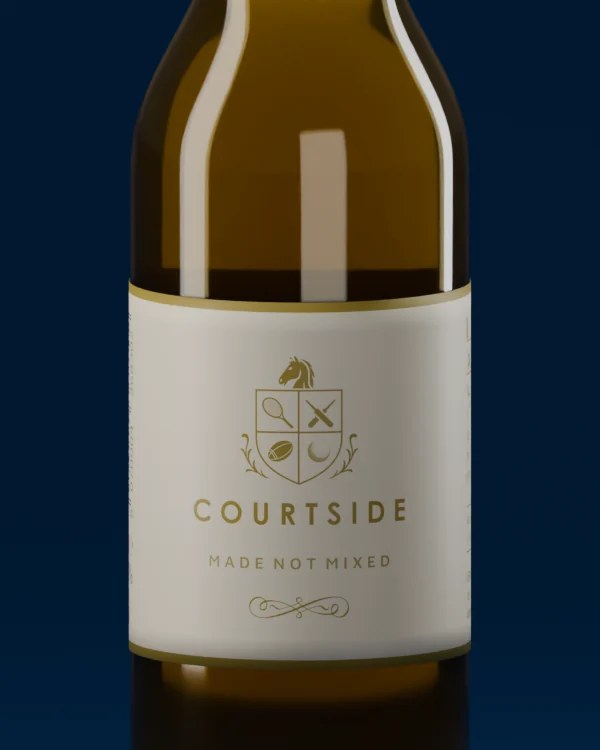 Close view of the Courtside label: the gold crest with tennis racquet, cricket bats, rugby ball and golf ball, the COURTSIDE wordmark and the line Made Not Mixed.